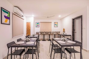 Un salón de conferencias con una larga mesa, sillas negras y una pizarra.