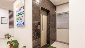 An elevator with a motivational sign, a framed certificate on the wall, and potted plants. - Treebo De Alphabet Gachibowli (Hyderabad)