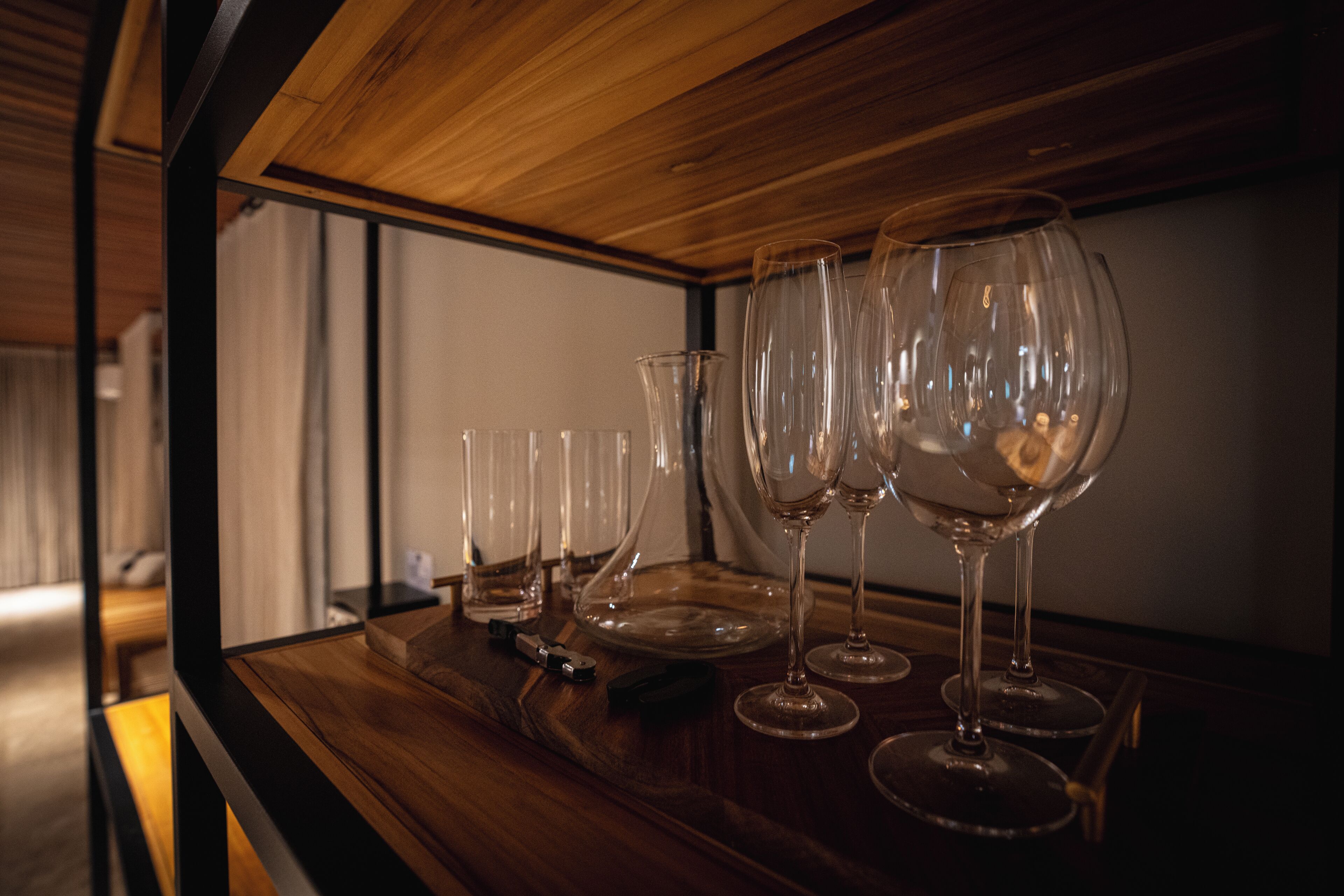 A wooden table with several wine glasses and a bottle opener.