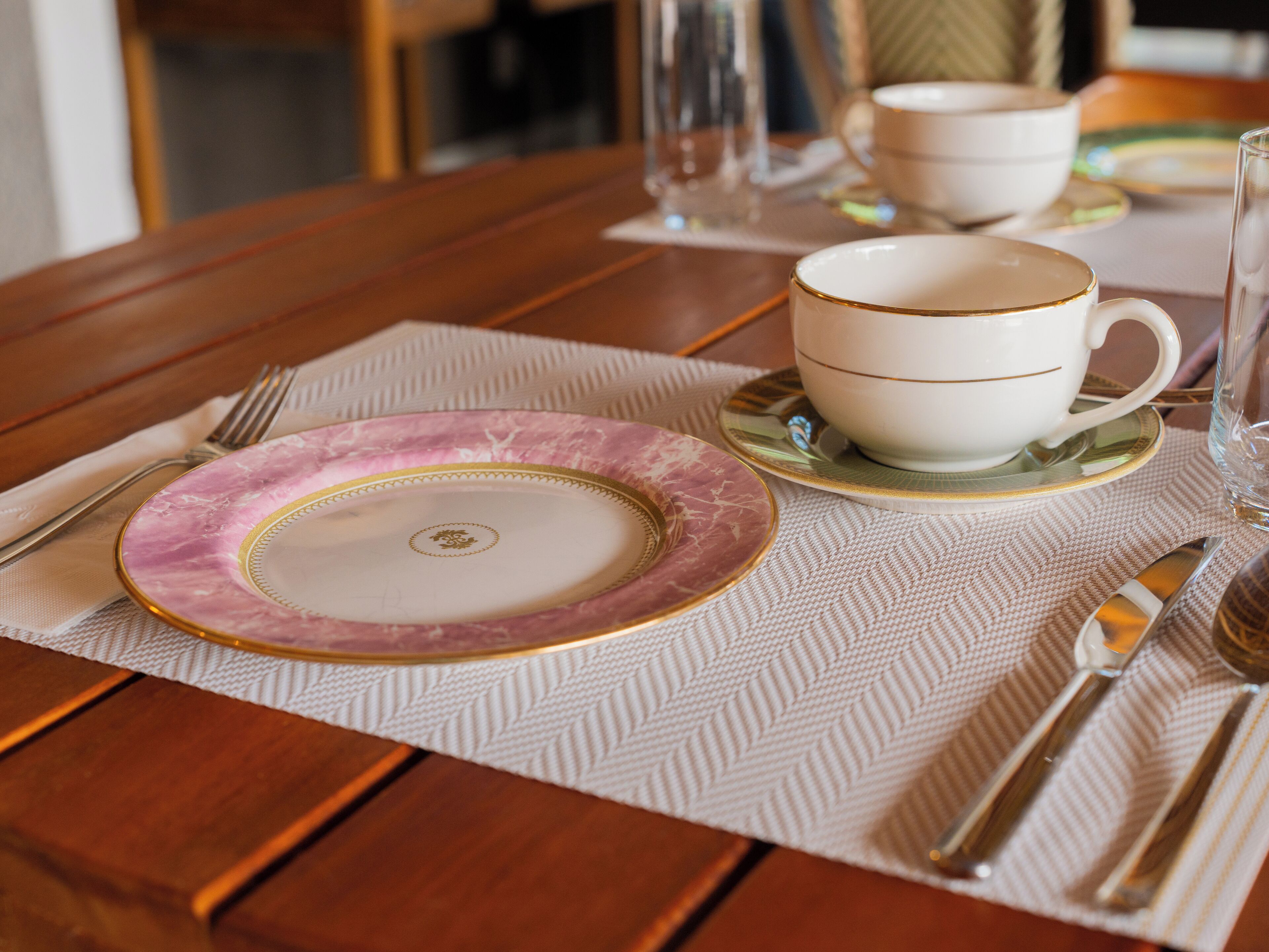 Una tavola apparecchiata con un piatto, una tazza, posate e un bicchiere.