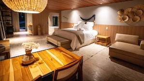 Un dormitorio amplio con una cama grande, techo de madera y un rincón comedor con mesa y sillas de madera.