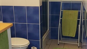 A bathroom with a toilet, a green towel rack, and a blue patterned rug. - Le Lagon 11 - Large T2 Sea and Bay View - SAINTE LUCE (Sainte-Luce)