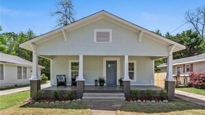 Une maison à deux étages avec un porche à l’avant, une porte centrale et une petite fenêtre située au-dessus de la porte.
