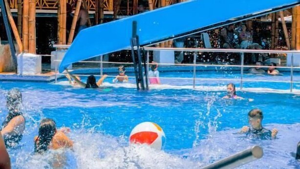 Ein Poolbereich mit einer Holzterrasse und einer blauen Rutsche.