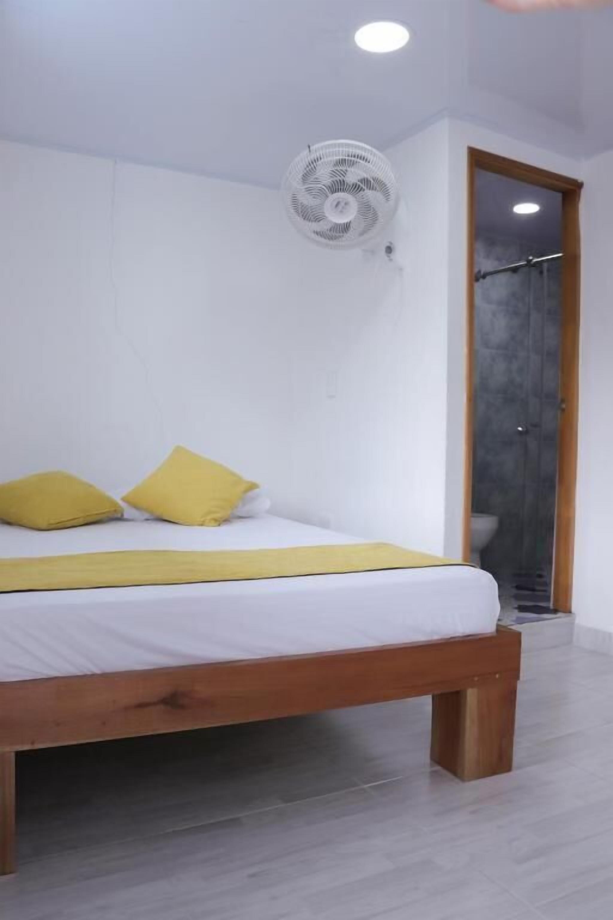 A bedroom with a bed, a fan, and a door leading to a bathroom.