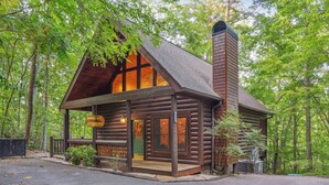 A log cabin with a porch, large windows, and a chimney.
