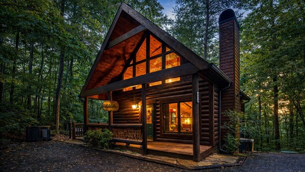 A log cabin with a large front porch, a chimney, and a sign indicating it is a lodge.