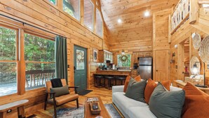 A wooden cabin interior with a living room, kitchen, and dining area.