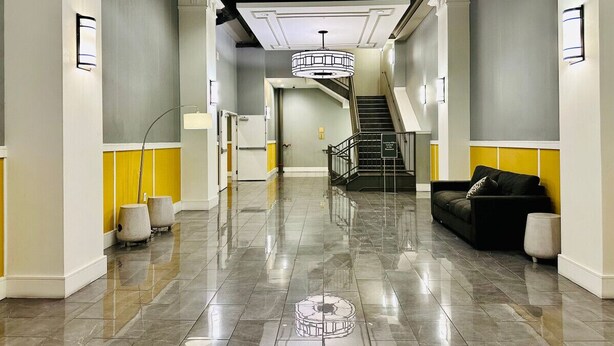 Eine großzügige Lobby mit poliertem Marmorboden, einer Treppe und einem schwarzen Sofa.