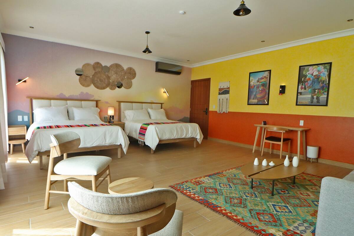A hotel room with two beds, a dining table, and a sofa.