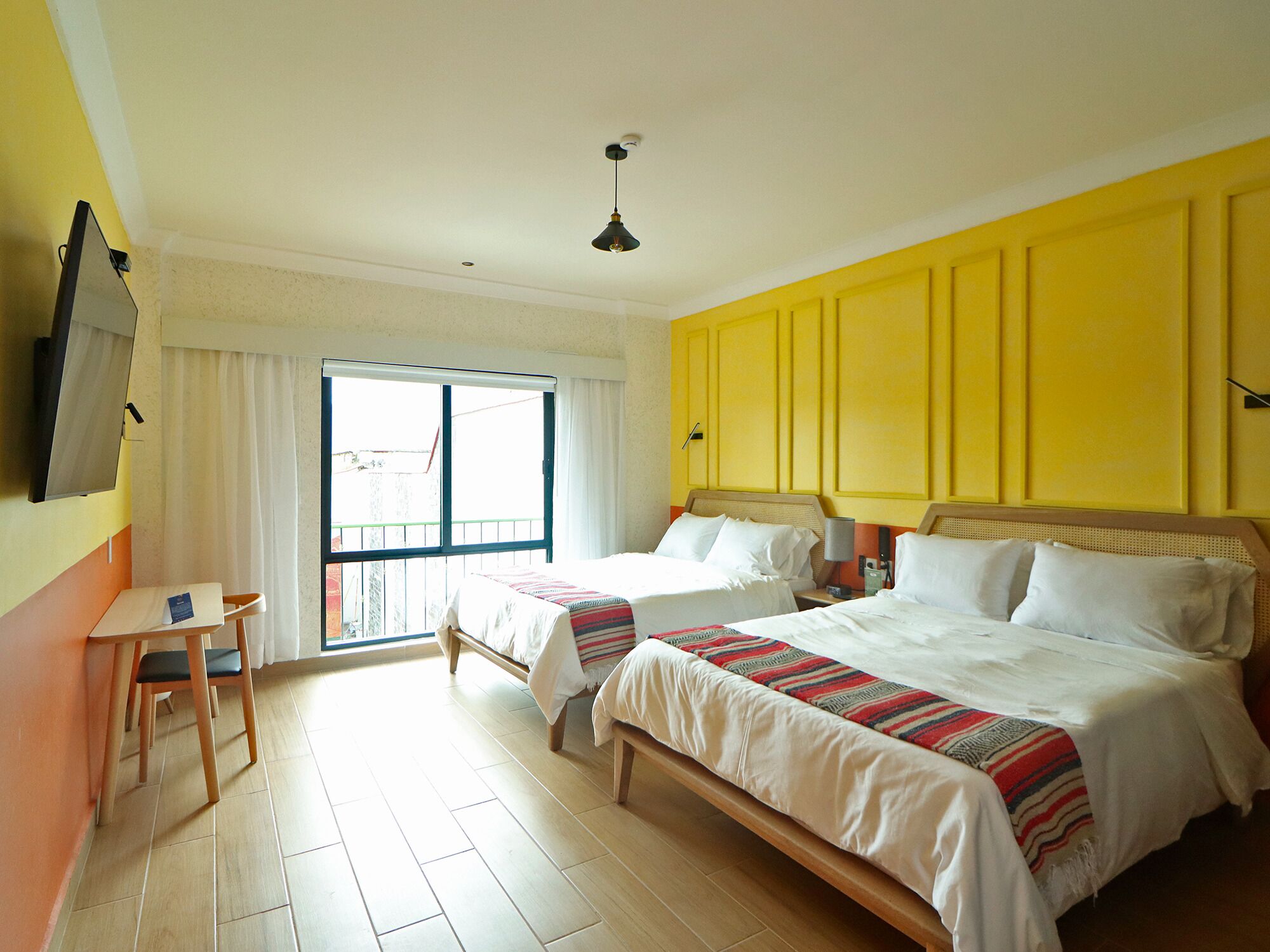 Una habitación de hotel con dos camas, una mesita y un televisor.