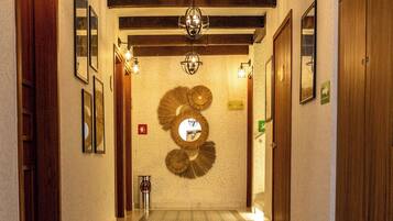 A hallway with patterned floor tiles, wooden doors, and a decorative wall piece.