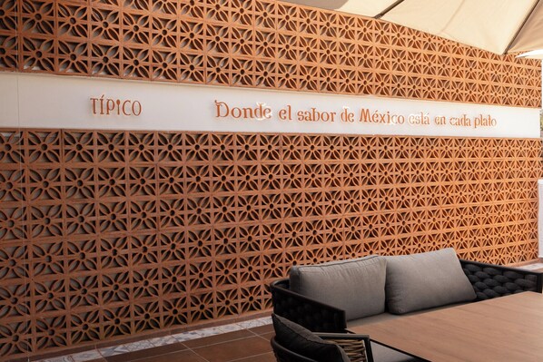 A wall with a geometric pattern and a sign that reads "TÍPICO Donde el sabor de México está en cada plato". - Hotel Boutique Típico (Orizaba)
