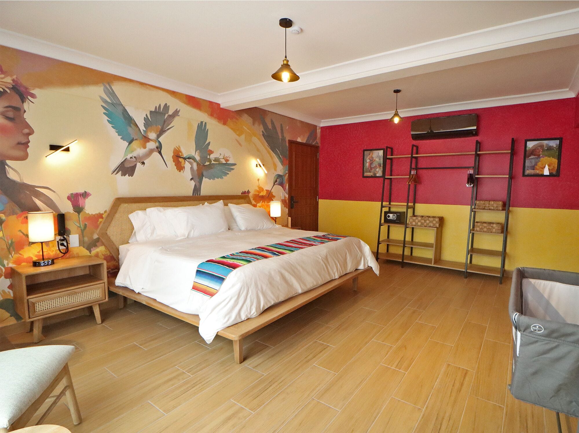 Habitación de hotel con cama, piso de madera, decoración en la pared, escritorio con lámpara y una silla.