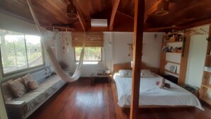 Ein Zimmer mit Hängematte, Bett, Sofa und Holzboden.