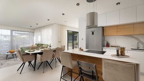Une cuisine moderne dotée d’un îlot central, d’un coin repas avec des chaises et offrant une vue sur l’extérieur.