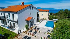 A modern building with a swimming pool, outdoor seating, and a view of the sea.