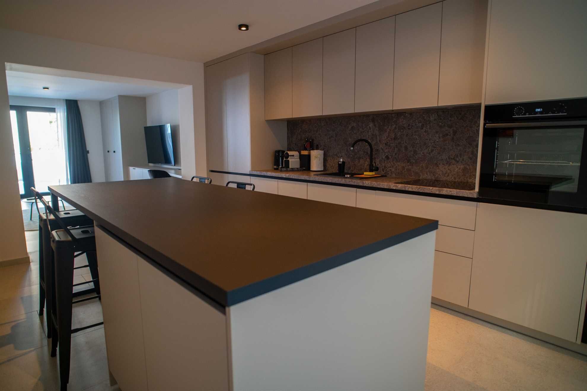 Una cocina moderna con una isla central, electrodomésticos integrados y un comedor con sillas.