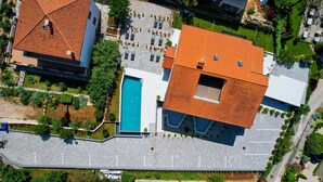An aerial view of a residential area with a swimming pool, a parking lot, and a building with a red-tiled roof. - Holiday apartment III. in Villa Calma Apartments with shared Pool (Zidarići (Krk))