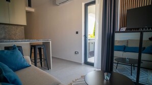 A modern living room with a sofa, a small round table, and a TV. - Holiday apartment III. in Villa Calma Apartments with shared Pool (Zidarići (Krk))