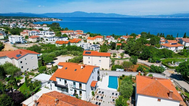 A coastal residential area with houses, a swimming pool, and a view of the sea. - Holiday apartment III. in Villa Calma Apartments with shared Pool (Zidarići (Krk))