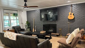 Ein modernes Wohnzimmer mit einer schwarzen Ziegelwand, einem Flachbildfernseher, einem Kamin und einer Wandgitarre.