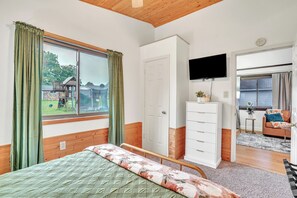 A bedroom with a bed, a TV, a wardrobe, and a view of the outside.