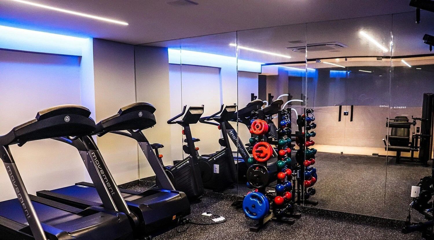 Un gimnasio con cintas de correr, elípticas y una zona de pesas.