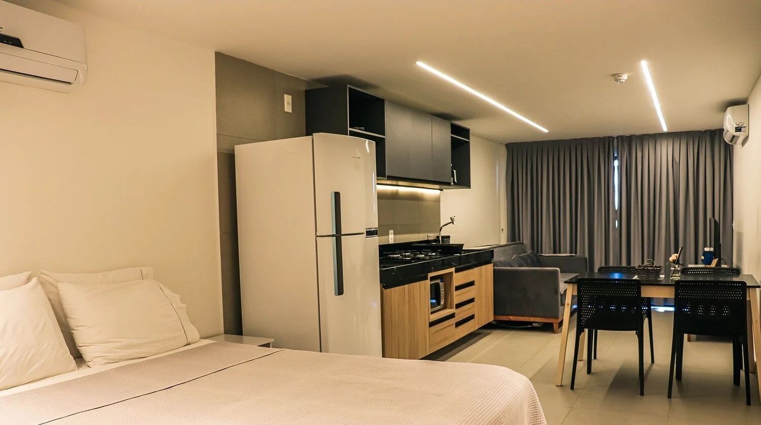 Et moderne hotelværelse med seng, tekøkken, spiseplads og udsigt over byen.