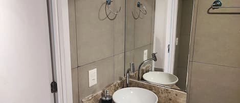 A bathroom with a white sink, a mirror, and a towel rack.