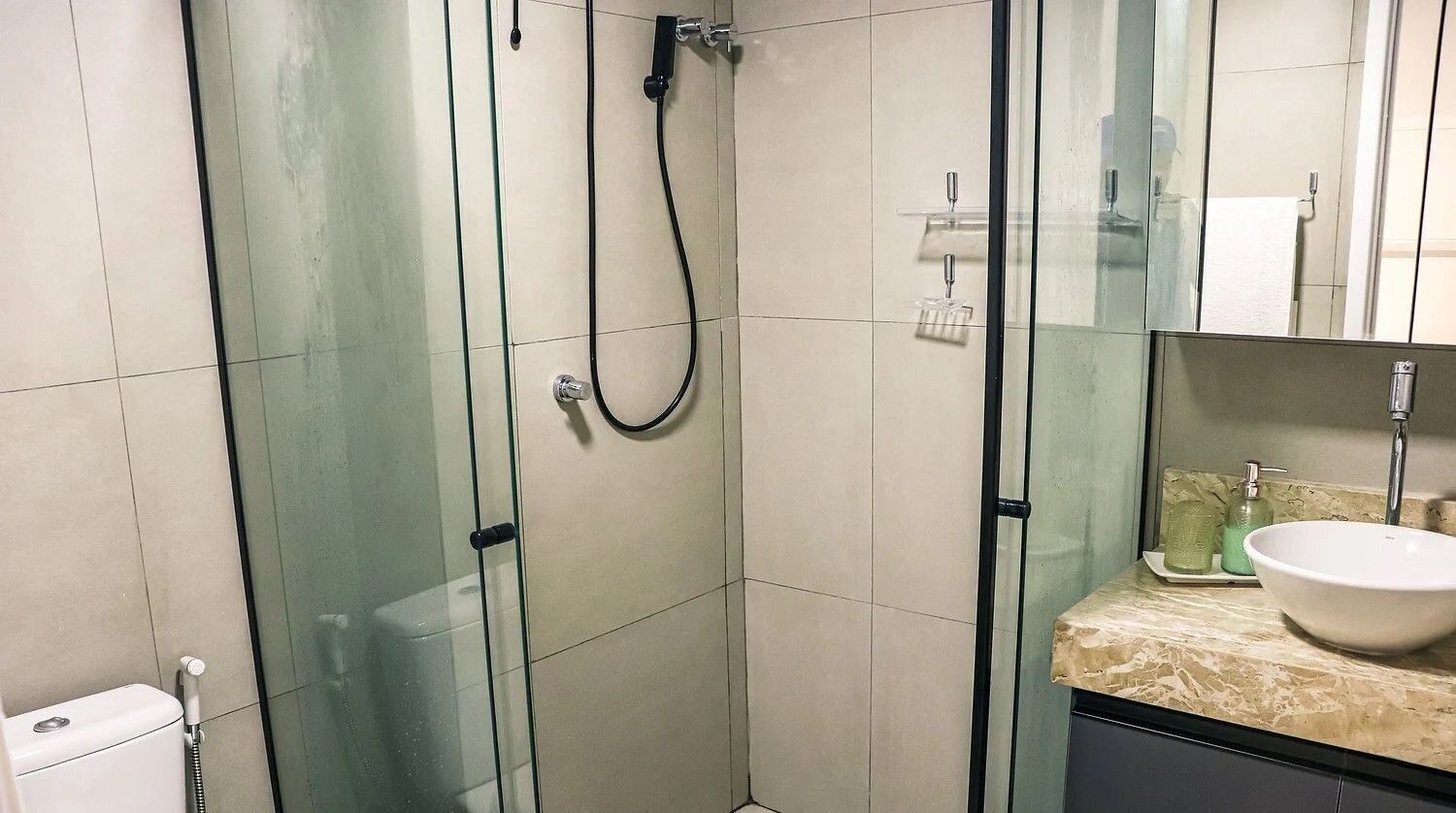 Un baño con ducha de vidrio, lavamanos con encimera de mármol y espejo.