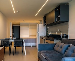 Eine moderne Küche mit eingebautem Herd, ein Essbereich mit Tisch und Stühlen sowie ein Wohnbereich mit einer Couch.