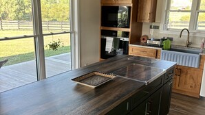 A kitchen with dark wood cabinets, a large island with a tray, and a view of a grassy area through the sliding glass doors.