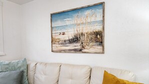 A beige sofa with two cushions, one light blue and one mustard yellow, against a white wall. - Robinhood Beach Villa (Sarasota)
