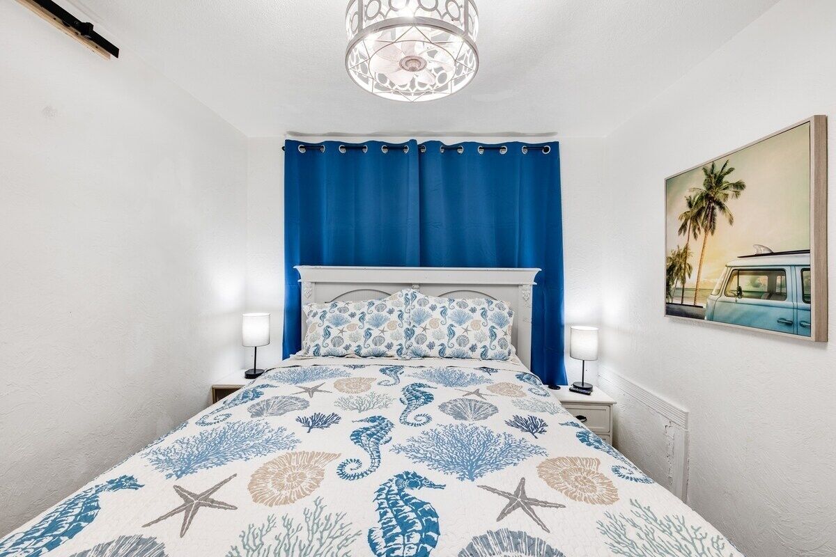 Una camera da letto con un letto, un comodino, una lampada, un quadro e un lampadario.
