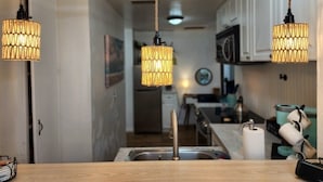 A kitchen with a wooden countertop, a stainless steel sink, and hanging pendant lights. - Robinhood Beach Villa (Sarasota)