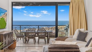 A balcony with a view of the sea, wicker furniture, a sofa, and a dining table. - Quivira PH 3BR Premium Condo w/ Golf Cart (Cabo San Lucas)