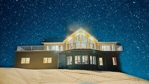 Et toetagers hus med balkon, store vinduer og en stjerneklar nattehimmel.