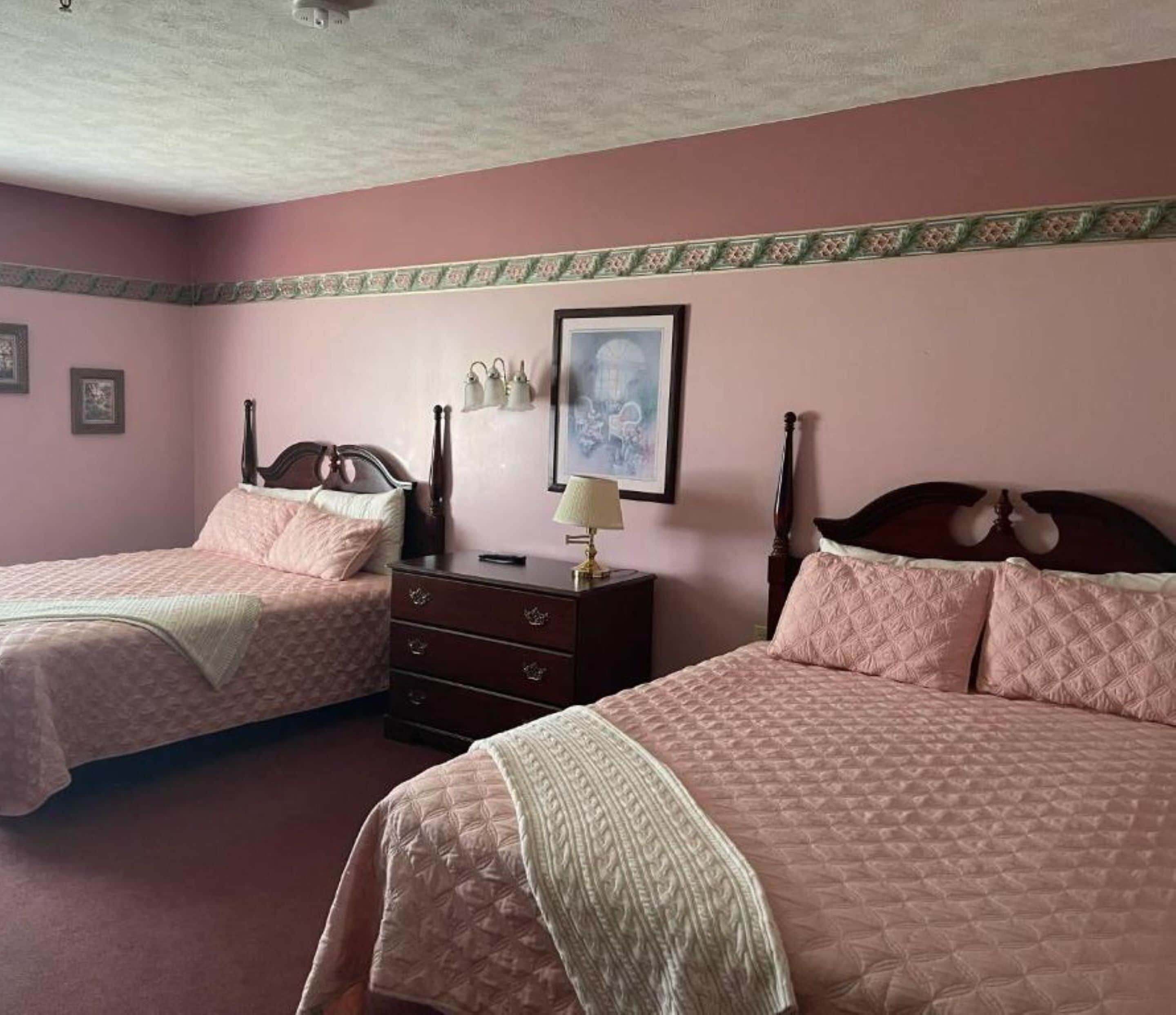 Ein Schlafzimmer mit zwei Betten, einem Schminktisch und einem gerahmten Bild an der Wand.