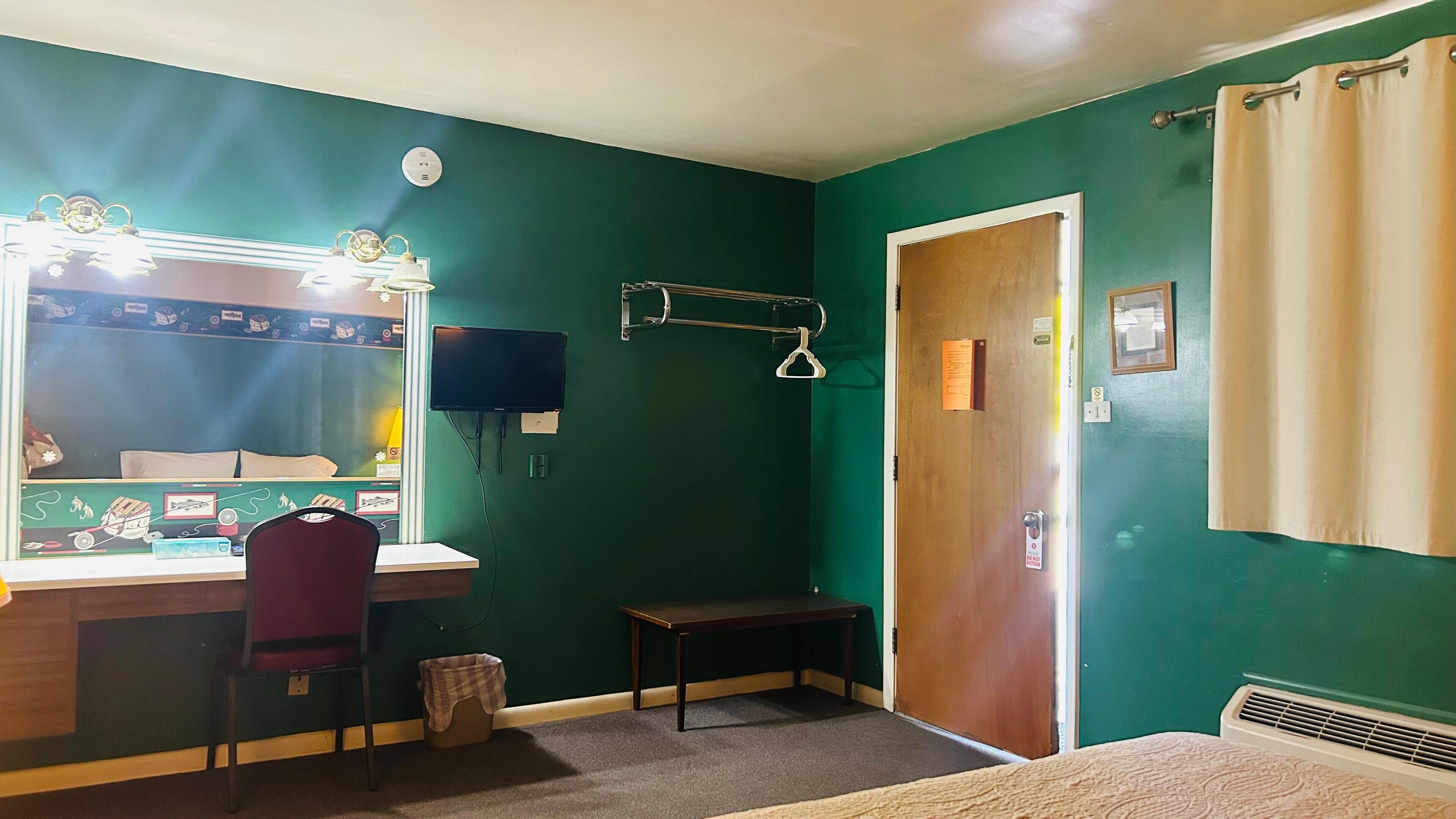A room with a vanity, mirror, and a bench.