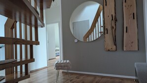 Un interno moderno con una scala in legno, uno specchio rotondo e una panca.