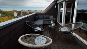 Una terrazza sul tetto con un divano, due poltrone e un tavolino.