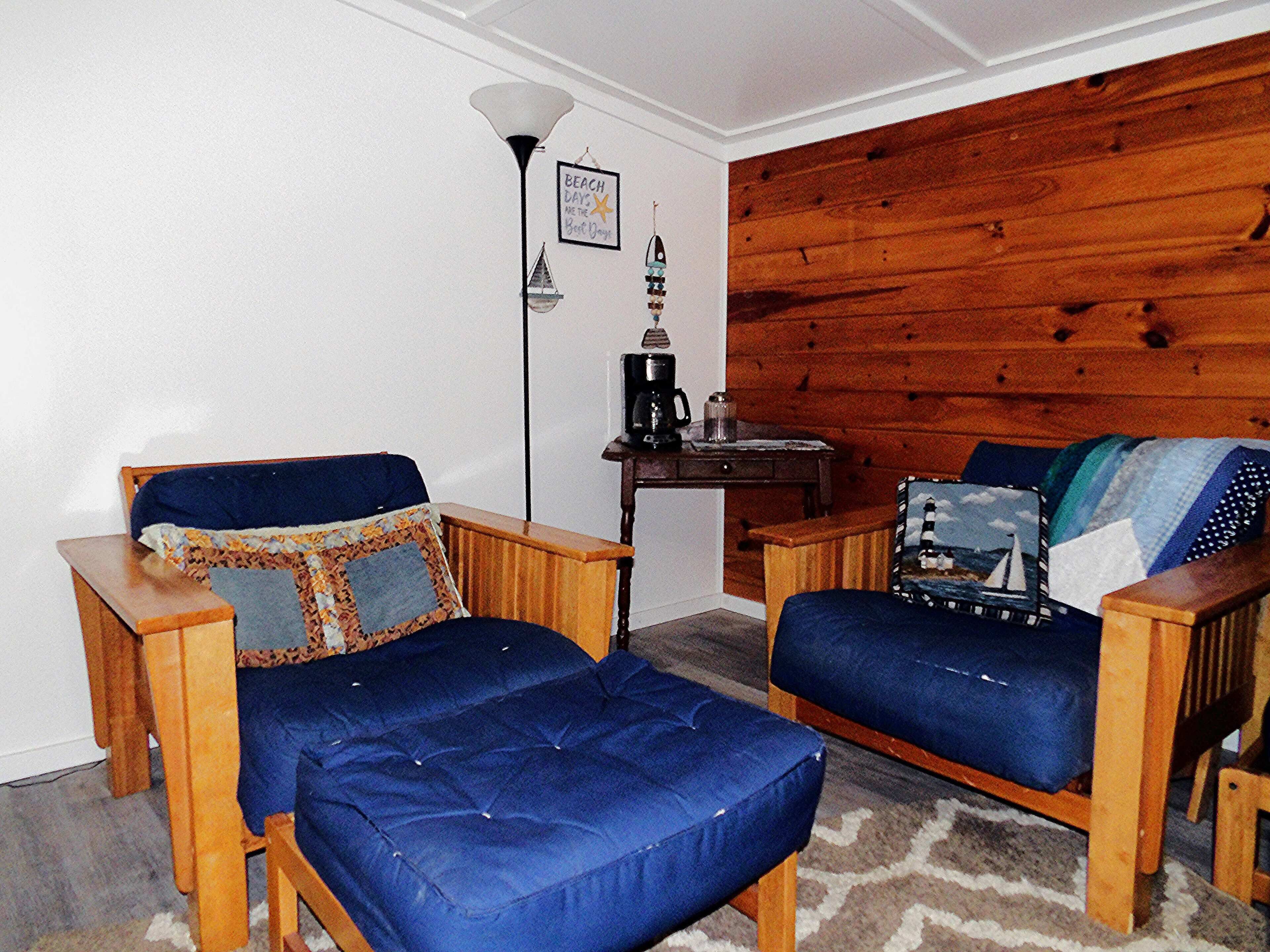 Una habitación acogedora con una pared de madera, un sofá azul, una mesa de centro de madera y una manta con estampado.
