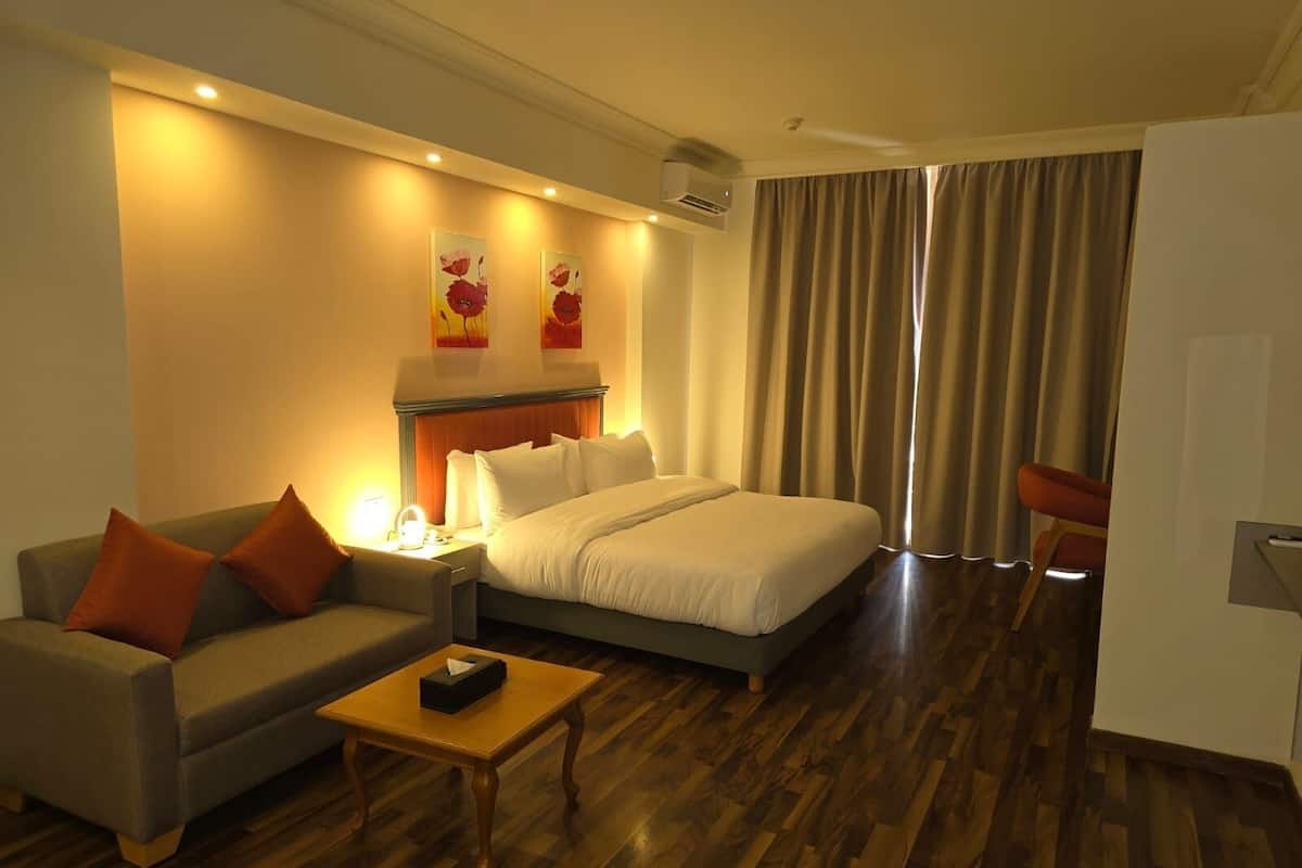 Una habitación de hotel con una cama, un sofá, una mesita y una silla.