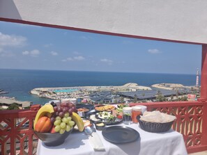 A balcony with a table set for breakfast, overlooking a coastal view with a lighthouse and beach. - Manara Riva Suites  (Beirut)
