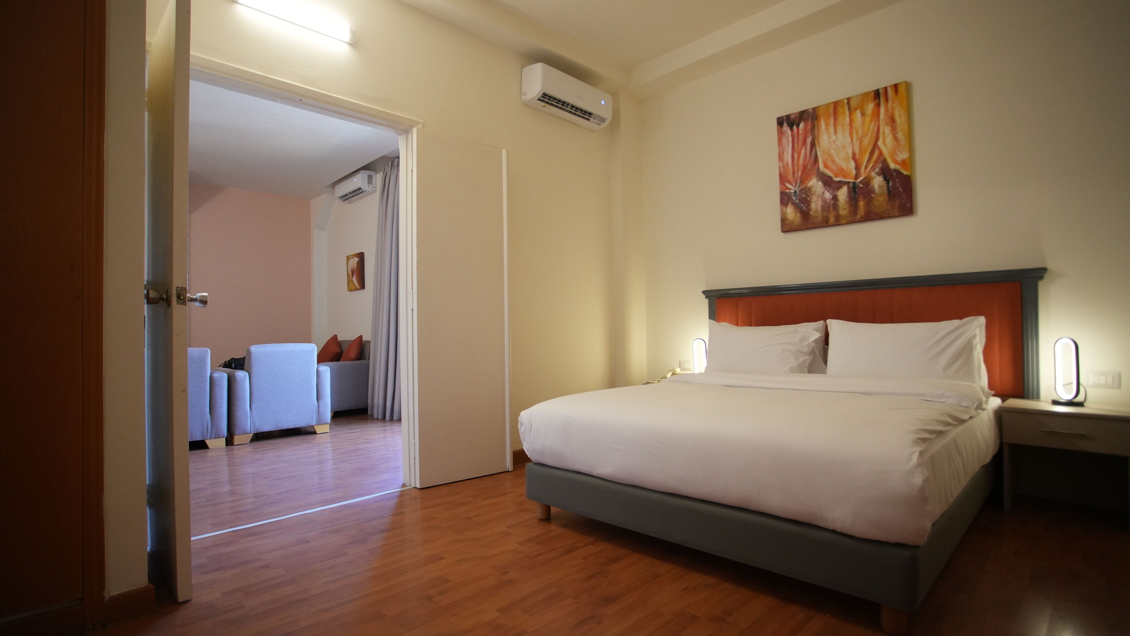 Una habitación de hotel con una cama, una mesita de noche y un cuadro en la pared.