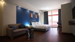 A hotel room with a bed, a sofa, a small table with fruit, and a balcony with a red railing. - Manara Riva Suites  (Beirut)