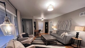 Een moderne woonkamer met een bank, salontafel en een eethoek op de achtergrond.