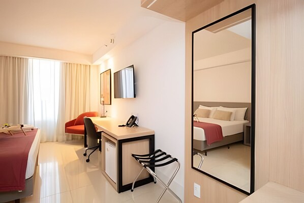 A hotel room with a desk, chair, bed, and a large mirror. - OZPED Flats Particulares Alvorada (Brasília)