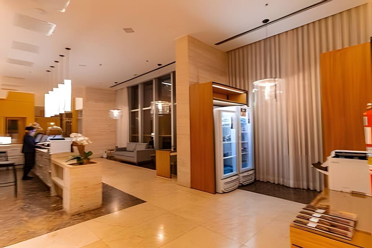 Un moderno vestíbulo de hotel con una recepción, zona de estar y un refrigerador.